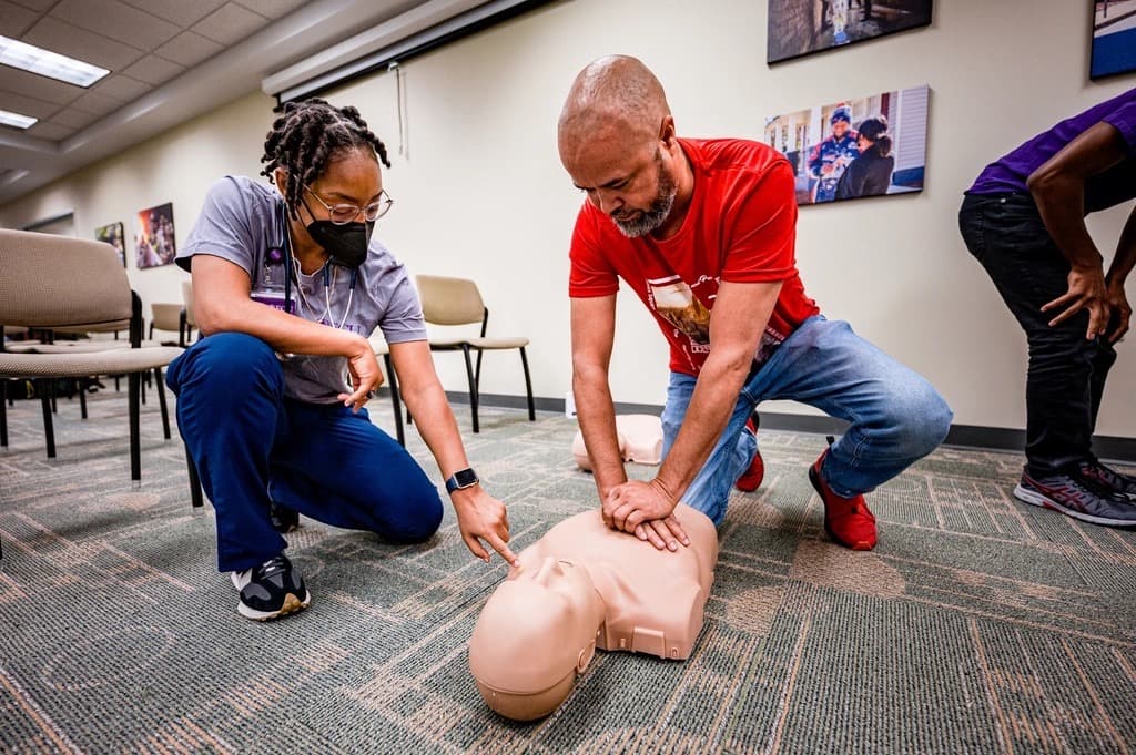 An instructor coaching a student through chest compressions during a CPR class.