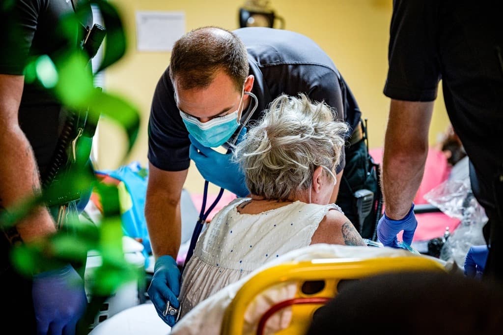 A paramedic assessing an elderly patient on a stretcher during a call.